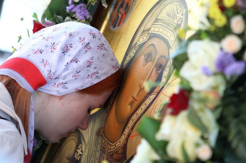 Girl bows to the icon of Our Lady