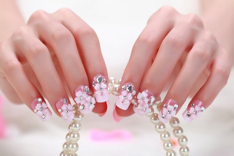 Bright pink manicure with acrylic flowers and rhinestones.